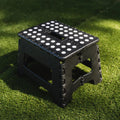 Black portable plastic foldable stool suitable for outdoor, bathroom, kitchen, adults, and kids, featuring a compact, lightweight design.