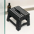 Black foldable plastic stool from Everything Baby, portable chair suitable for outdoor, bathroom, kitchen, and kids’ use.