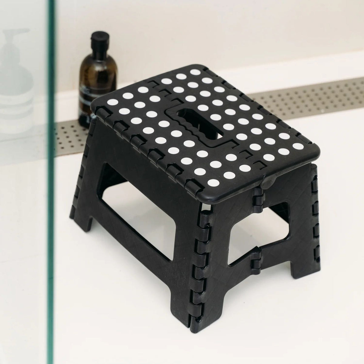 Black foldable plastic stool from Everything Baby, portable chair suitable for outdoor, bathroom, kitchen, and kids’ use.