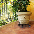 Heavy duty iron plant stand with wheels holding a round flower pot, suitable for indoor and outdoor use.