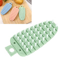 Green carrot-shaped vegetable brush for scrubbing potatoes, fruits, and vegetables, ideal for kitchen cleaning.
