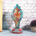 Colorful glass bird feeder with a bird design, suitable for outdoor gardens, attracting hummingbirds and garden birds.