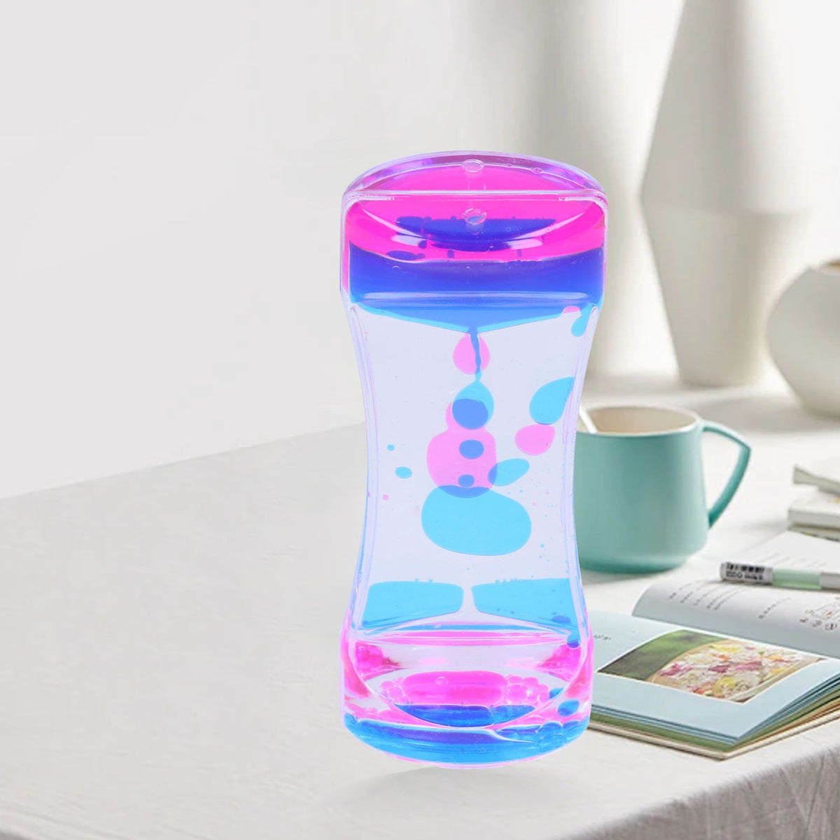 Blue and pink double color liquid motion bubbler hourglass toy for kids, featuring flowing liquid bubbles for desk decor and pretend play.