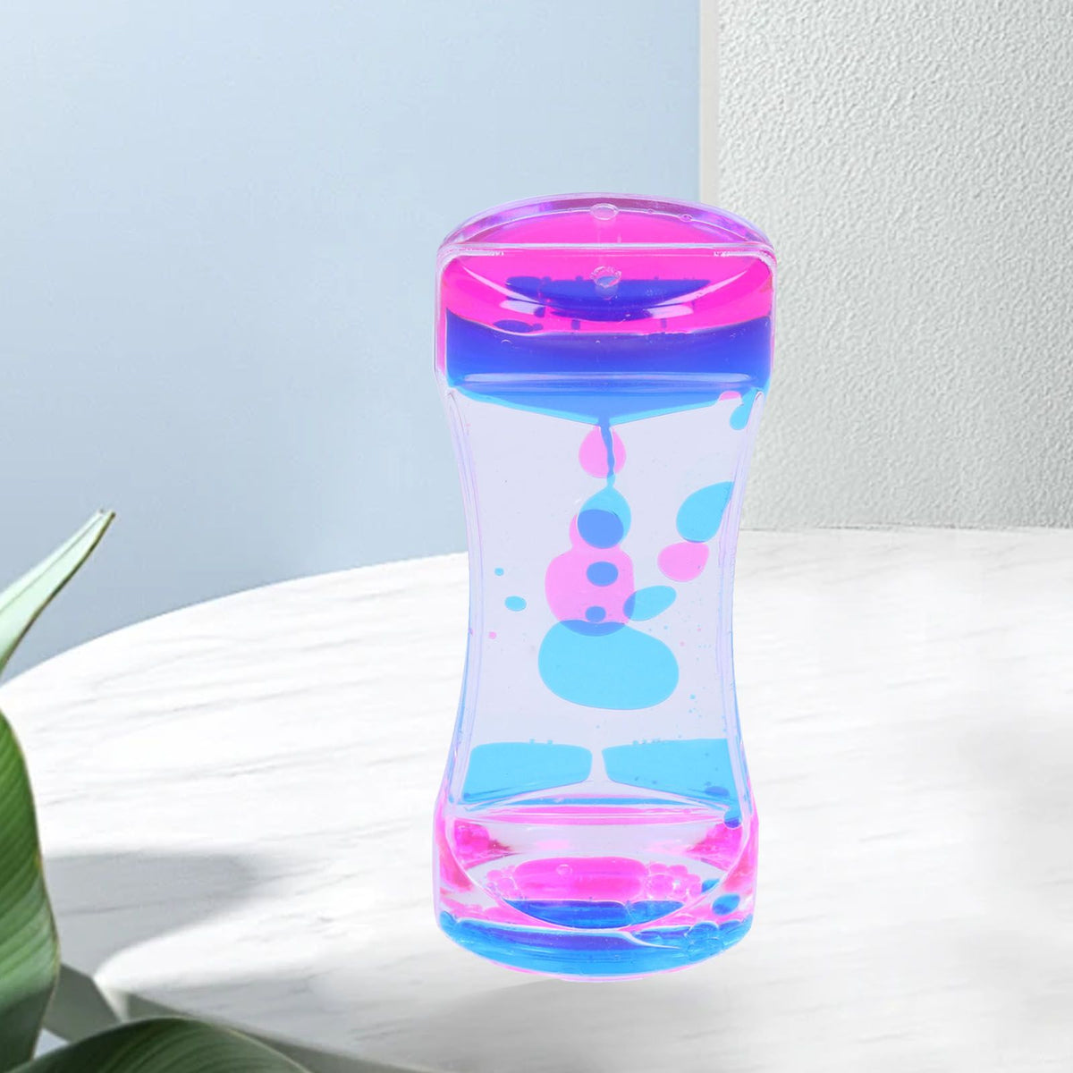 Blue and pink double color liquid motion hourglass timer toy for kids, with bubbling liquid for pretend play and desk decor.