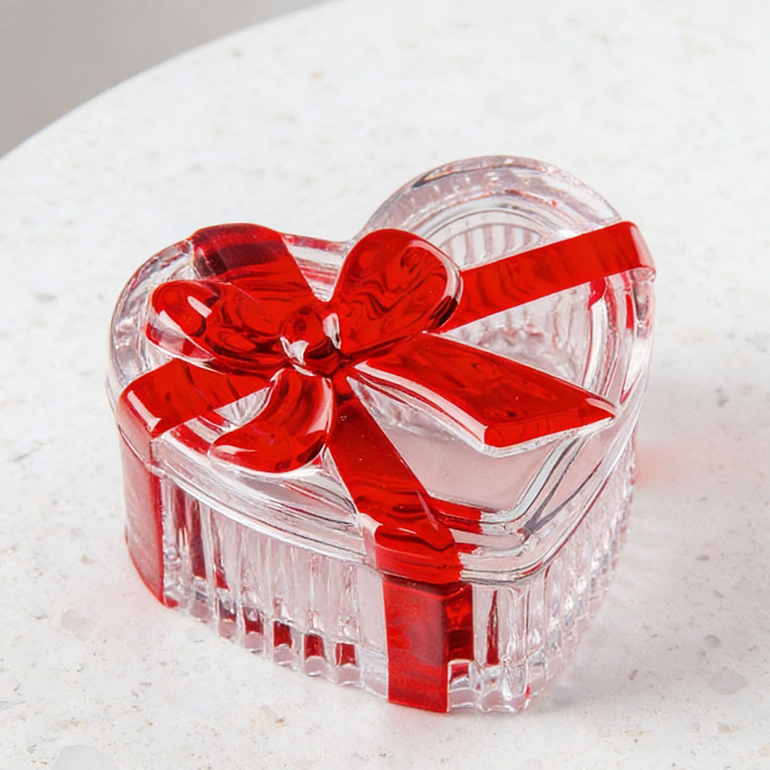 Clear glass heart-shaped candy jar with lid and red bow, suitable for snacks, jewelry, and storage in baby and kids nursing spaces.