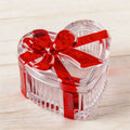 Clear glass heart-shaped candy jar with lid and red bow, perfect for storing snacks, jewelry, or small items.