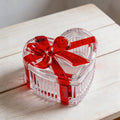 Glass heart-shaped candy jar with lid featuring a red bow, ideal for storing snacks, jewelry, or small items.