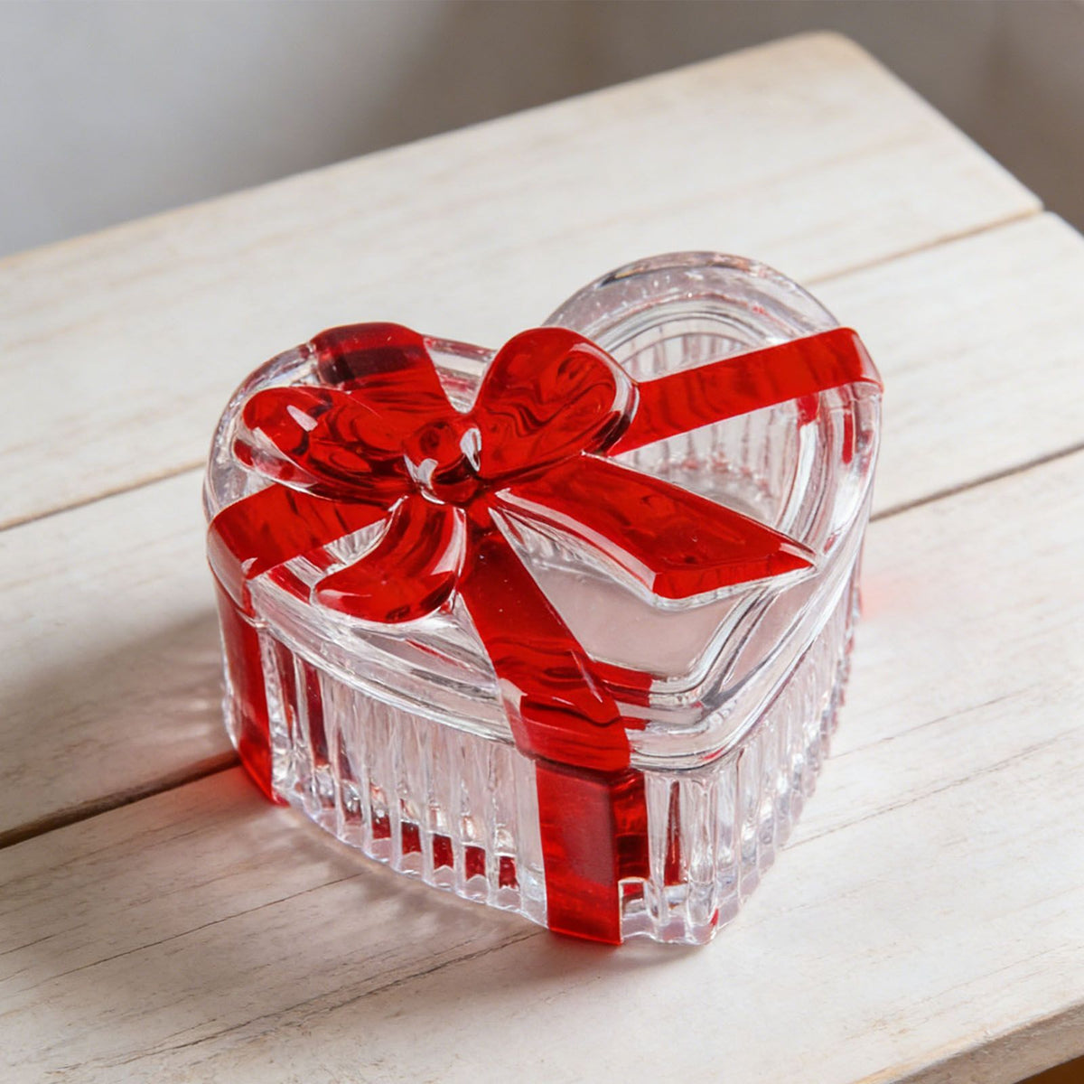 Glass heart-shaped candy jar with lid featuring a red bow, ideal for storing snacks, jewelry, or small items.