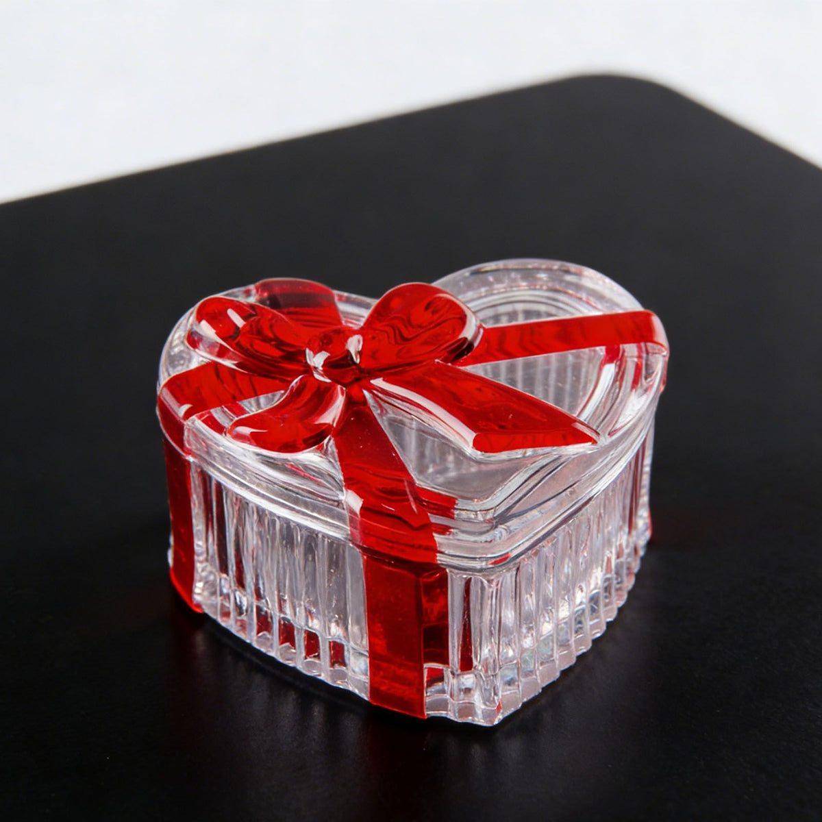 Clear glass heart-shaped candy jar with lid and red bow, ideal for storing snacks, jewelry, or small items.