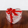 Clear glass heart-shaped candy jar with lid and red bow, perfect for storing snacks, jewelry, or candies.