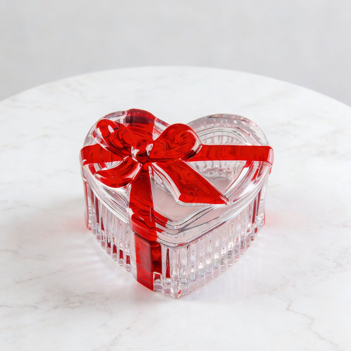Clear glass heart-shaped candy jar with lid and red bow, ideal for storage of snacks, jewelry, or small items.