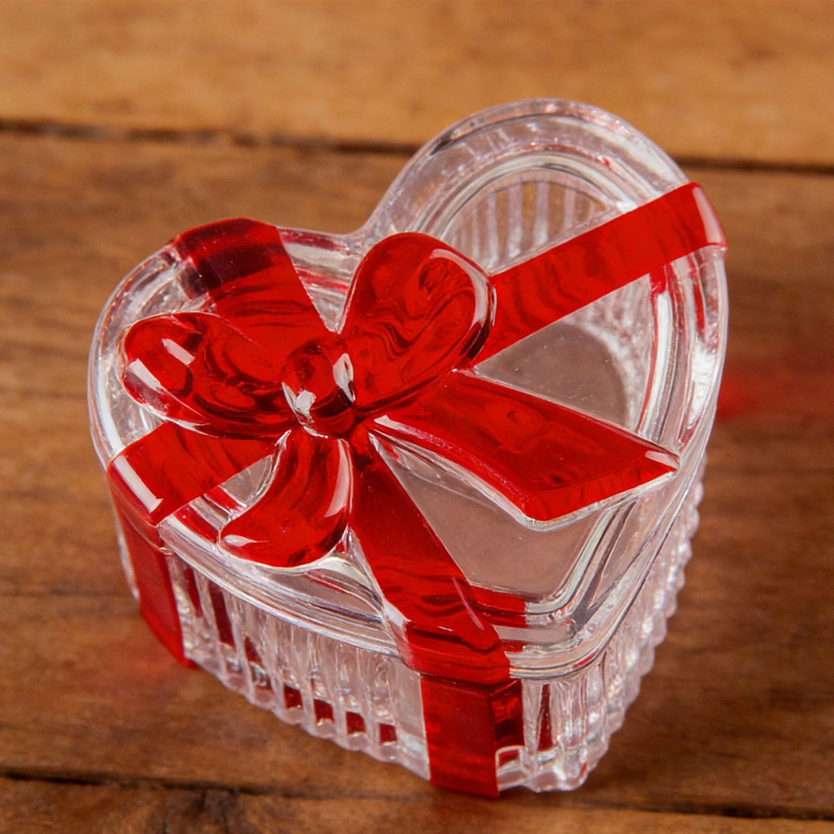 Clear glass heart-shaped candy jar with lid and red bow, ideal for storing candies, snacks, or jewelry in a decorative serving dish.