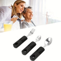 Three-piece stainless steel baby adaptive tableware set with rubber grip handles, featuring fork and spoon for feeding assistance.