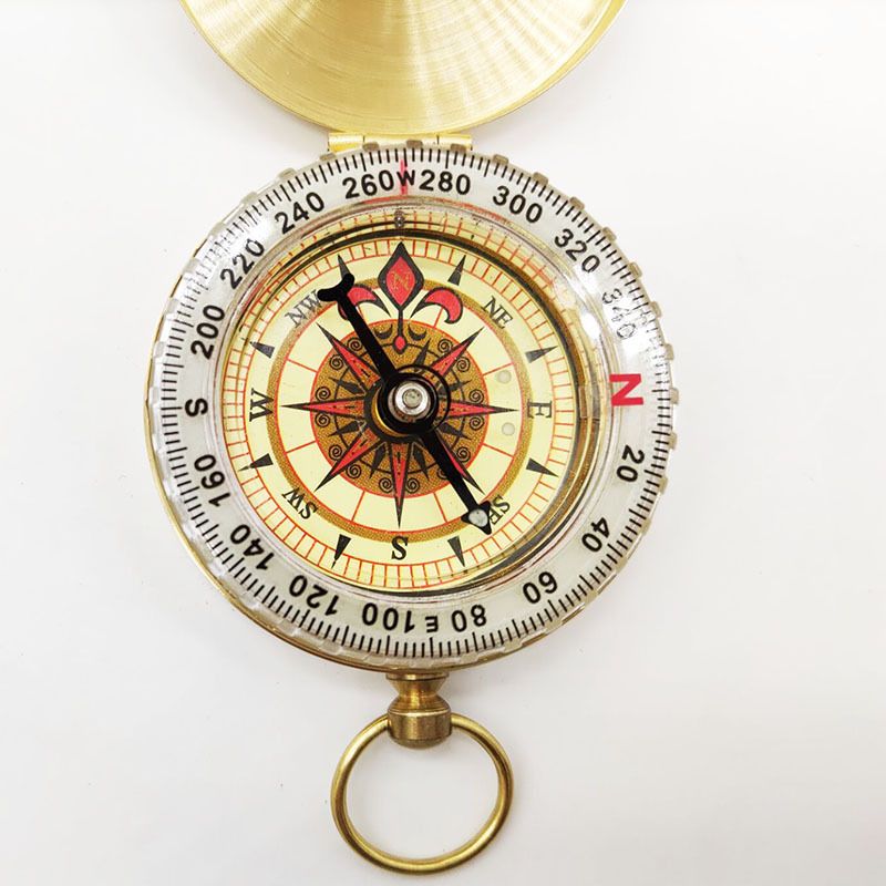 Gold brass pocket compass for camping and hiking, outdoor navigation tool, suitable for wilderness backpacking and survival activities.