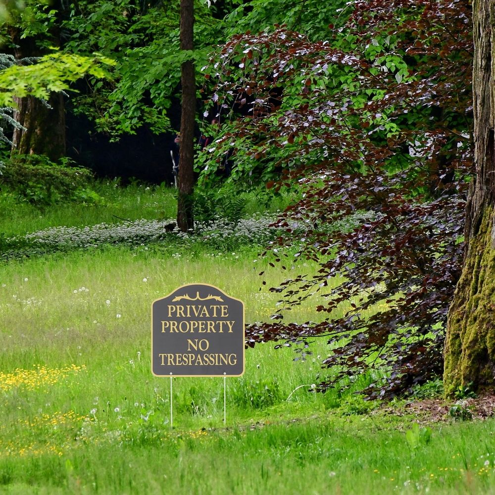 Black metal no trespassing sign with stake for outdoor yard and garden security, suitable for safety and boundary marking
