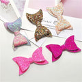 Five colorful glitter hair bows for baby girls and toddlers, featuring sequins and large designs, from Everything Baby.