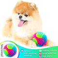 Two light-up dog balls with spikes, LED glow, and squeaker, designed for fetch and play, featuring elastic tennis ball construction.