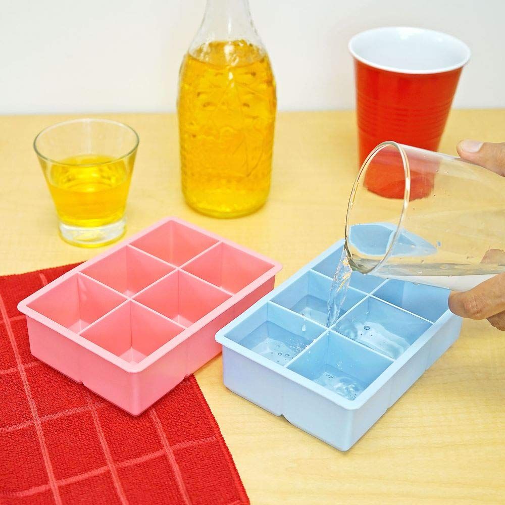 Pink and blue square ice cube trays by Everything Baby, used for making large ice cubes for drinks in a colorful kitchen setting.
