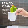 Baby bottle brush set with bottle, nipple, detail, and straw brushes for cleaning baby bottles on a drying rack.