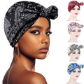 Baby girl wearing a pink beanie with a bow, turban style headwear, cozy sleeping cap for girls from Everything Baby.