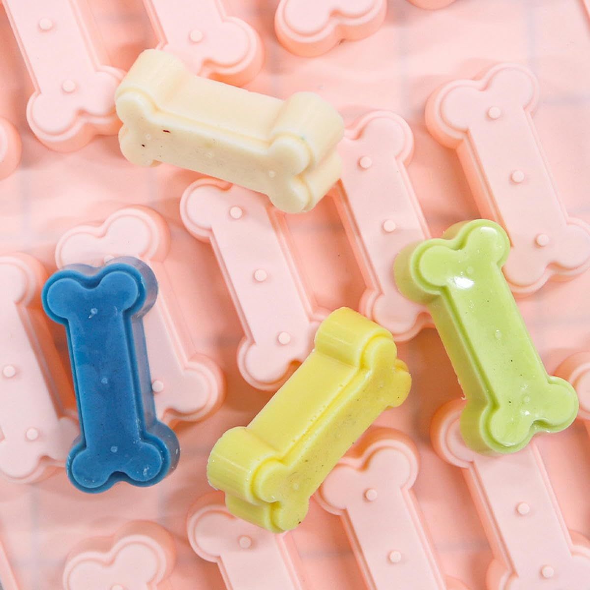Two silicone molds shaped like small bones for making homemade dog and cat treats, ideal for baking pet-friendly chocolates and candies.