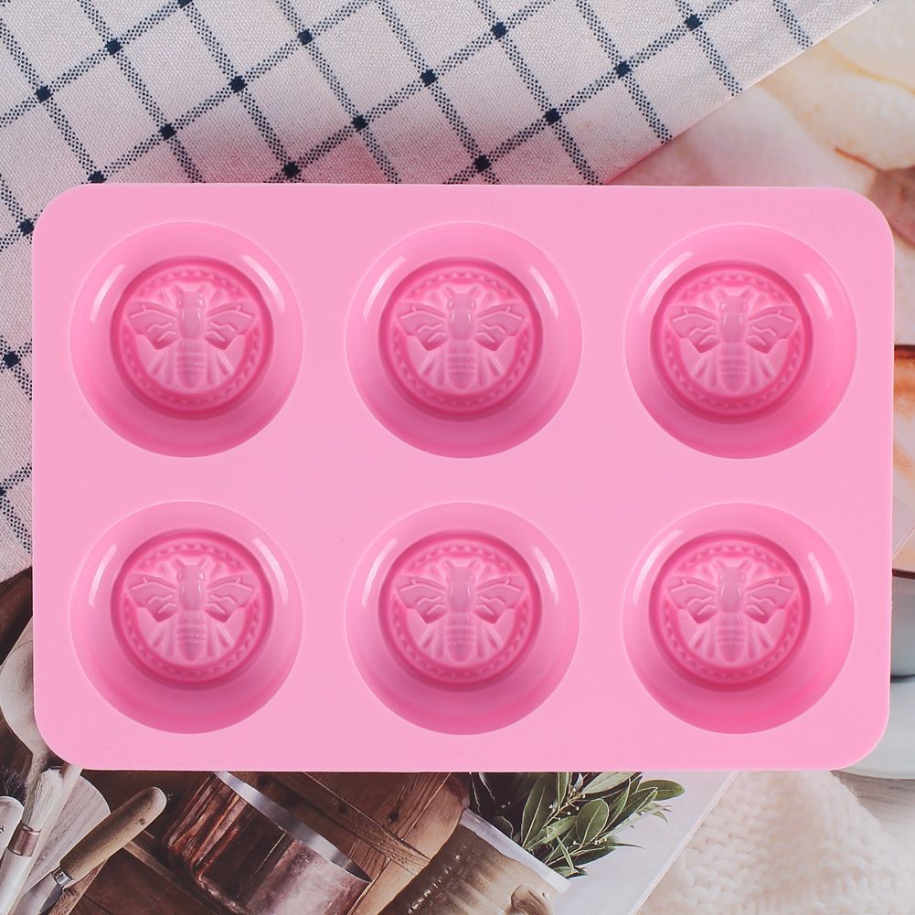 Pink round silicone mold with honeybee design for making soaps, lotion bars, jello, bath bombs, and chocolates.