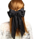 Black satin hair bow barrette with long ribbon for girls, stylish hair clip accessory for parties and special occasions.