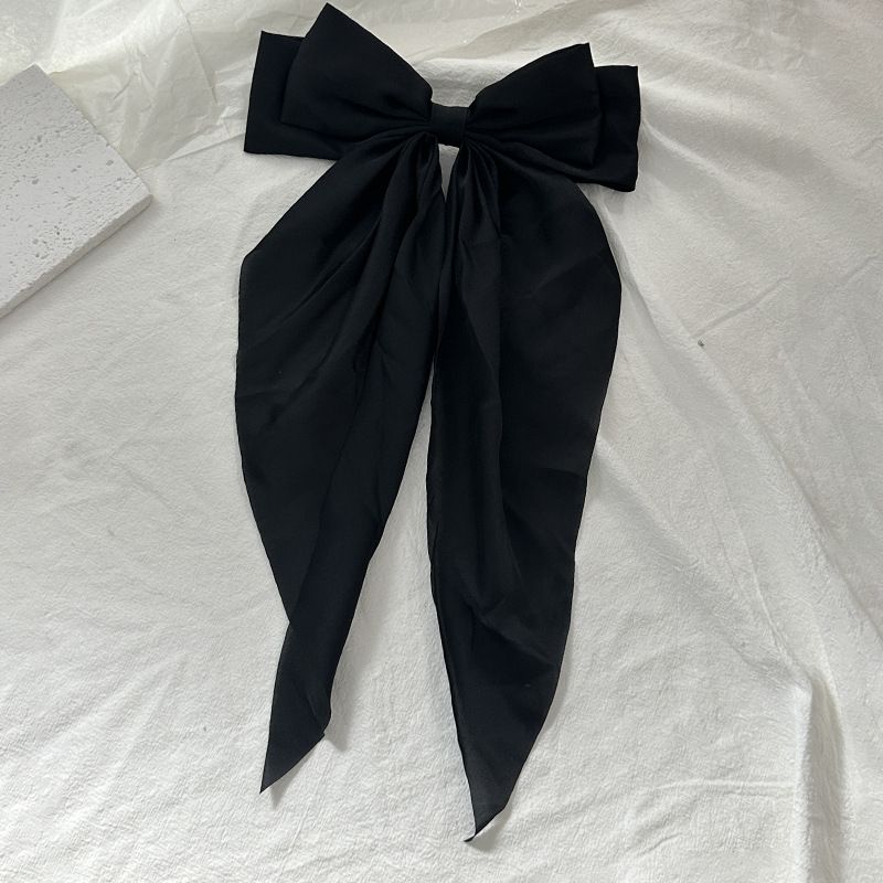 Black satin hair bow barrette with long ribbon for girls, stylish hair accessory for parties and special occasions.