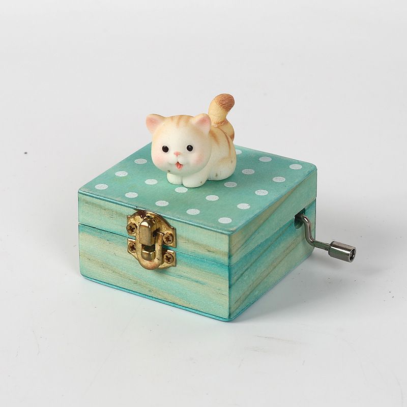 Gift wrapped mini wooden music box with a cat design, hand crank, playing "Castle in the Sky," in brownish yellow for kids' pretend play.