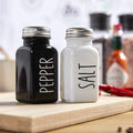 Cute glass salt and pepper shakers set with stainless steel lids, black and white farmhouse style, perfect for kitchen decor.