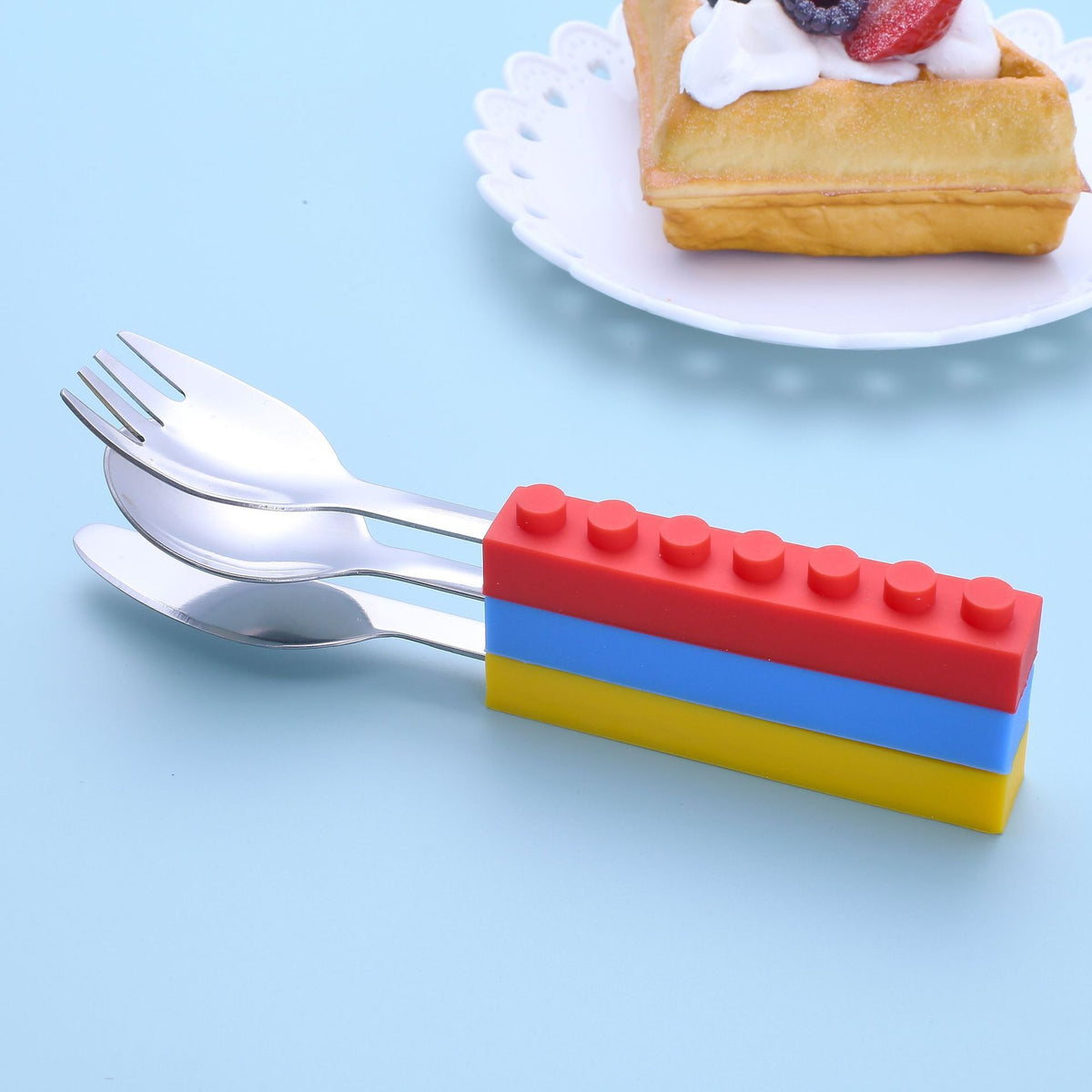 Set of three toddler utensils with interlocking brick design, including fork, spoon, and knife for kids' mealtime.