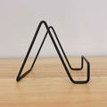 Metal square wire stand for cutting boards, cheese platters, or cookbooks, with a sturdy holder design for kitchen or serving use.
