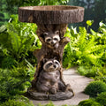Resin raccoon birdbath for garden, antique-style polyresin bird bath with raccoon design in a home yard setting