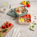 Green Monbento Flex kid's lunch box with two compartments and cutlery, featuring a natural design for children.