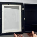 Set of two black wooden art display frames for kids' artwork, ideal for storing and showcasing drawings and creative projects.